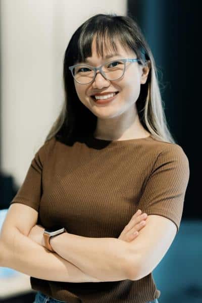 A woman in a brown shirt smiling into the camera.