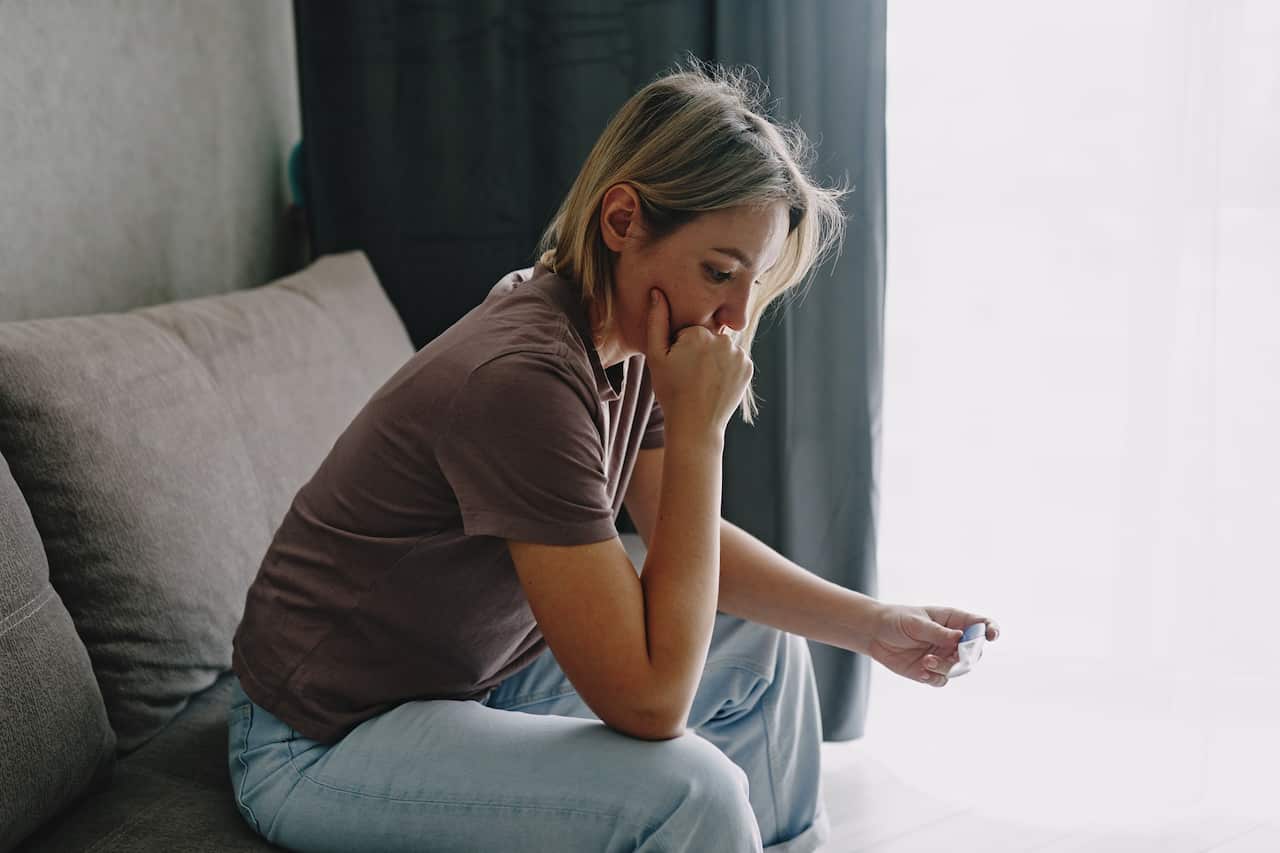 A young woman holds a device reading a pregnancy test.