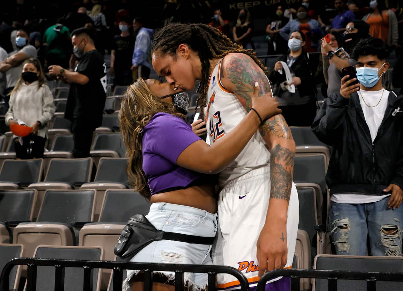 Woman kissing another woman inside a stadium.