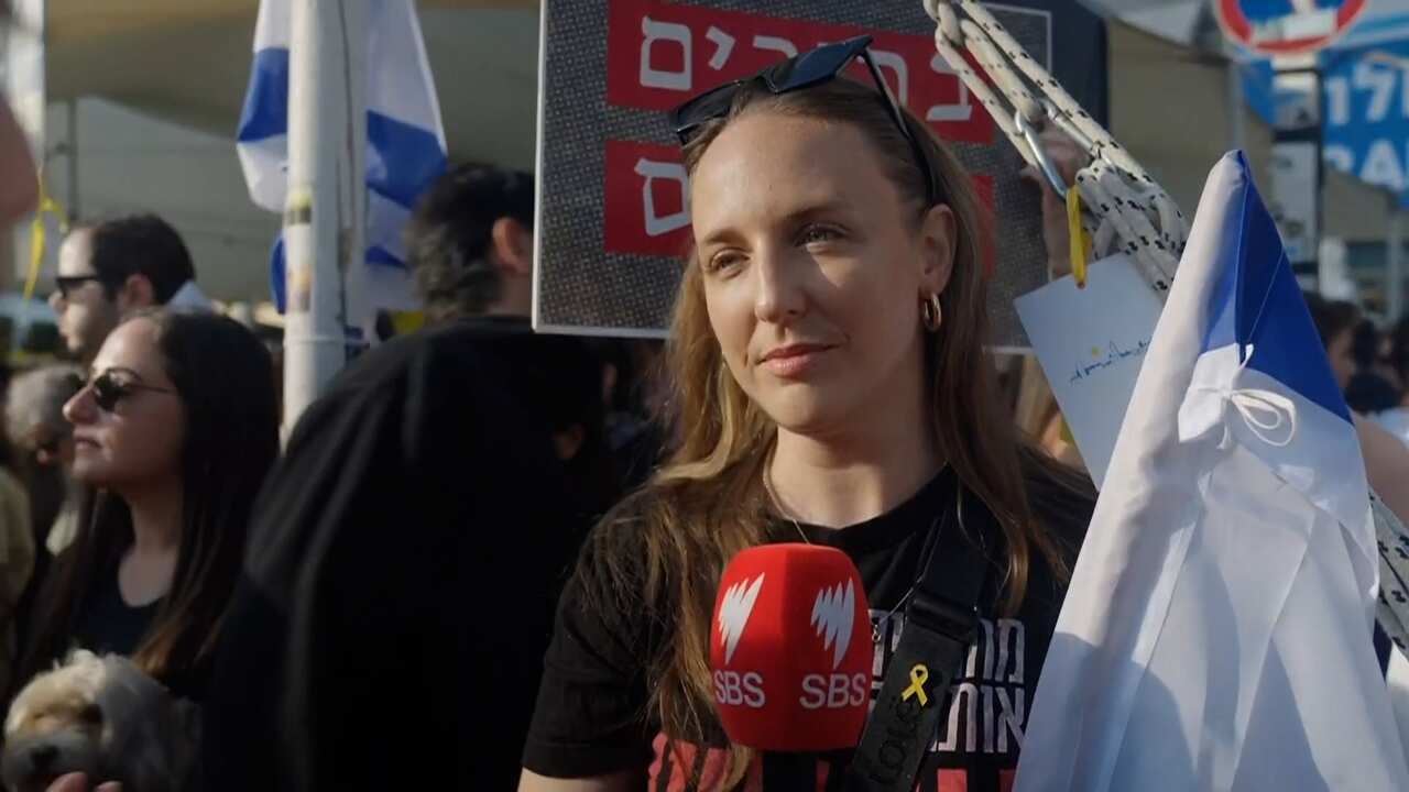 A woman in a black shirt speaks to the media