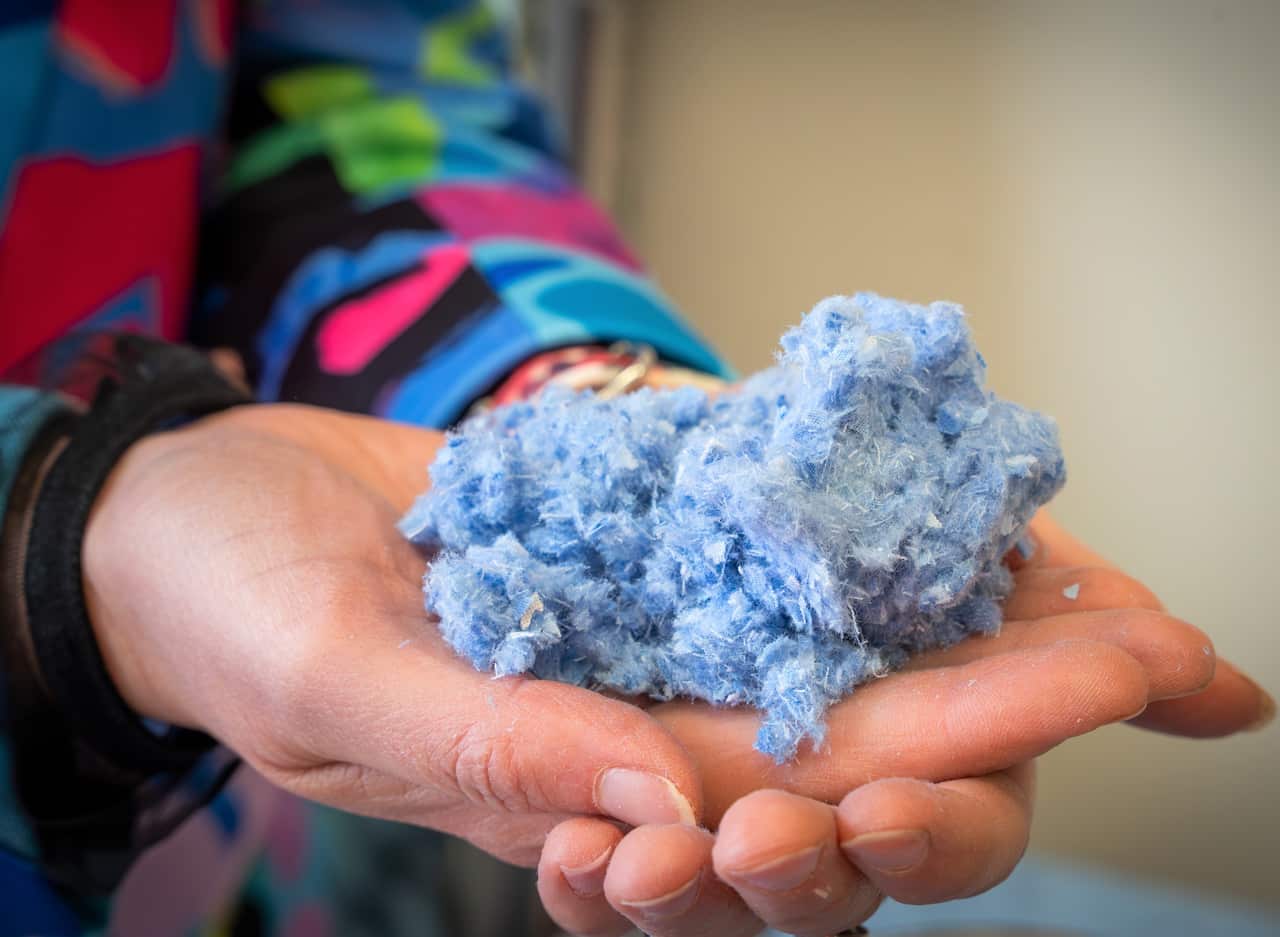 A hand holding a mound of blue fibres.