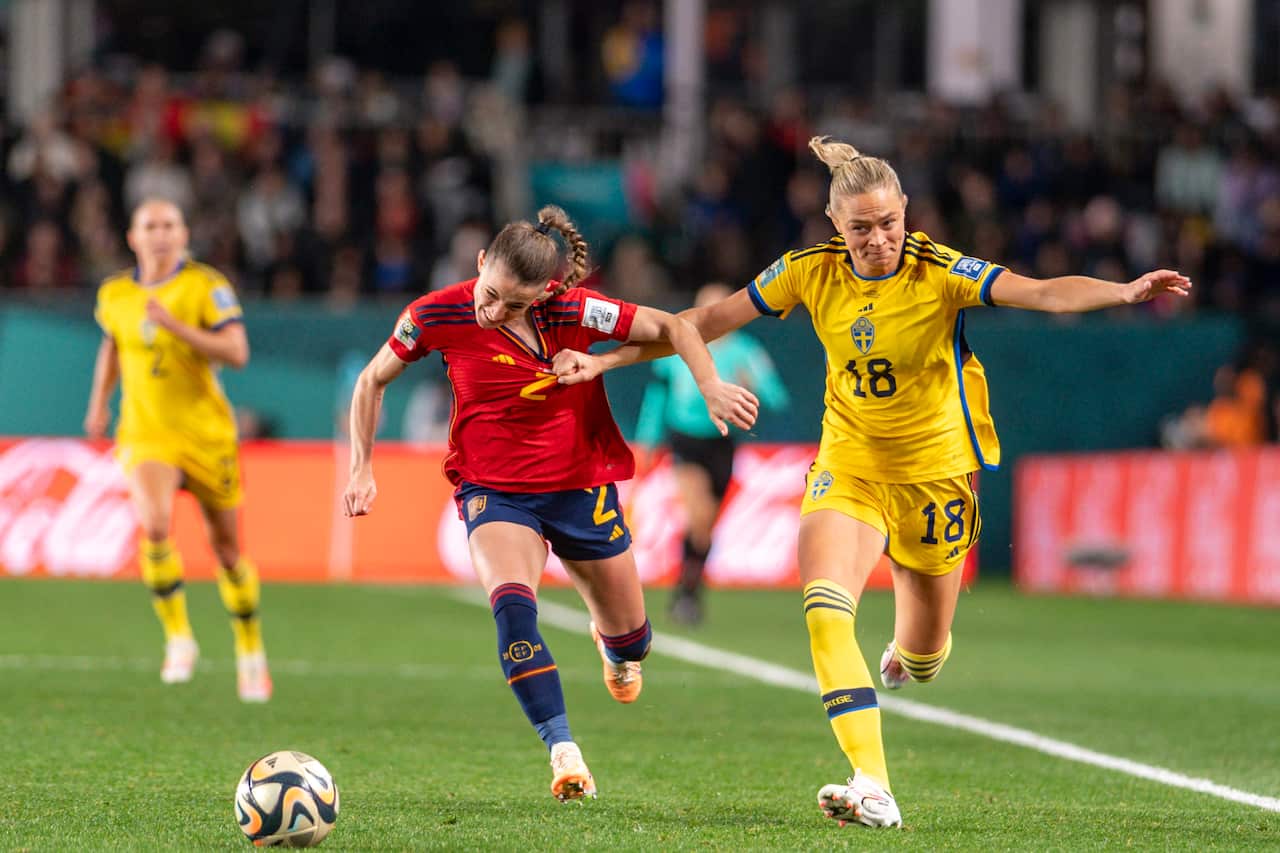 Players from the Swedish and Spanish women's football teams running on the field.
