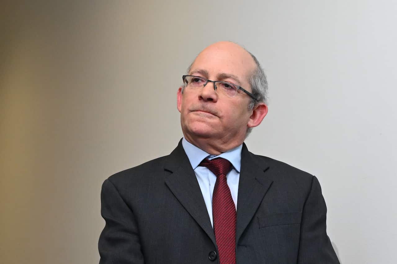 A man in a black suit, white shirt and red tie