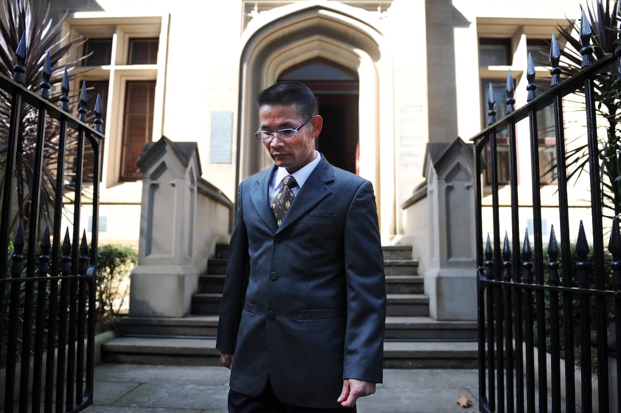 A man in a suit outside a stone building