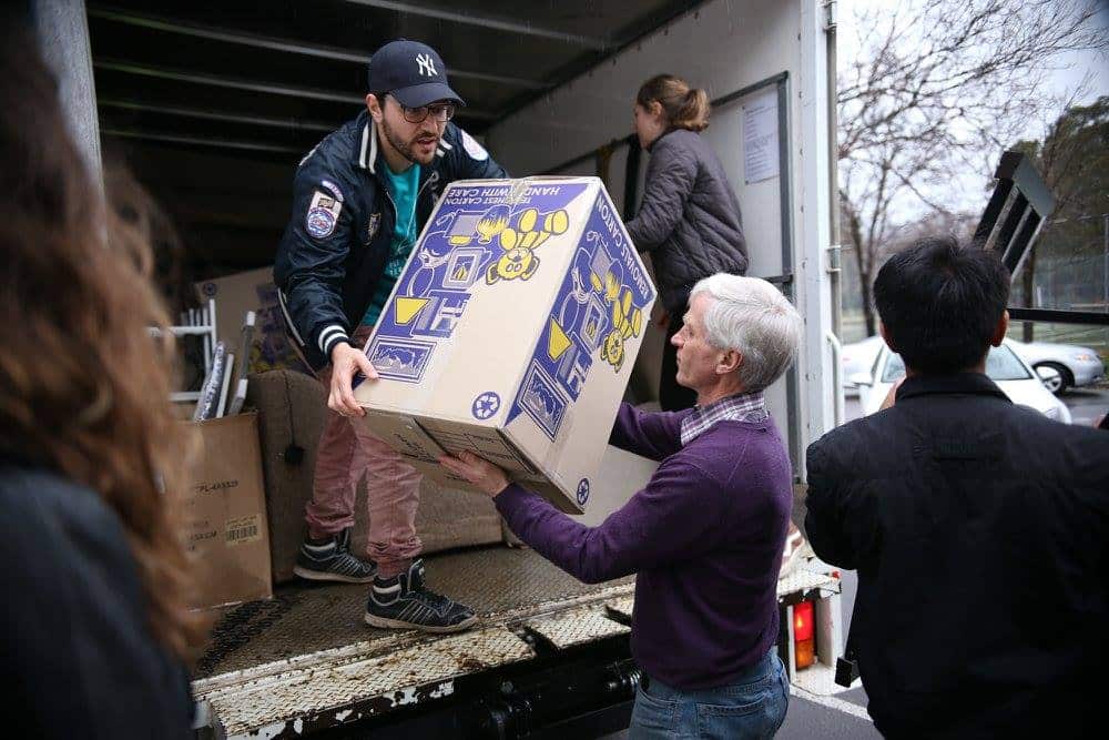A man is seen carrying boxes out of a truck, as another man helps.jpg