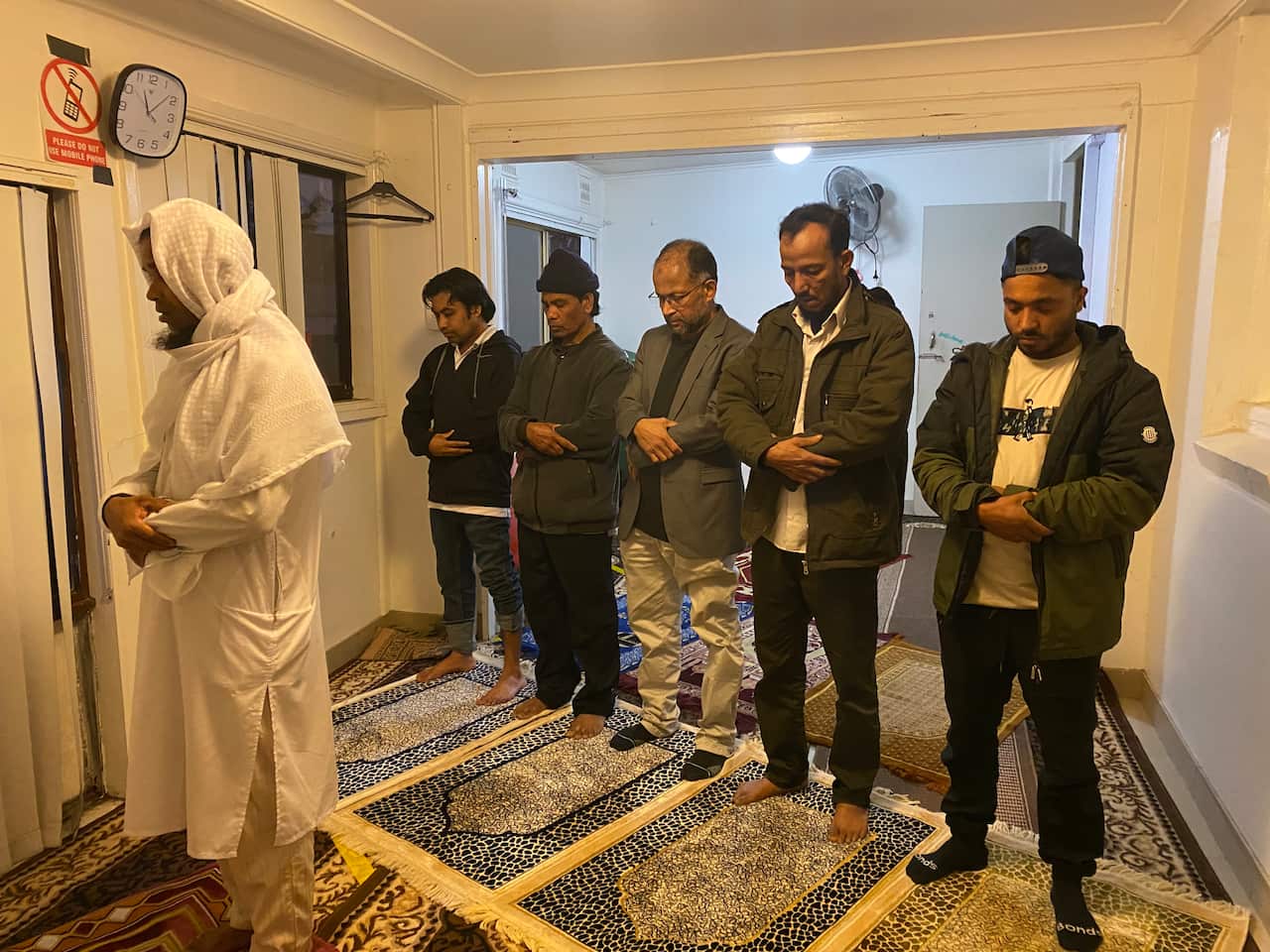 A small group of men praying indoors 