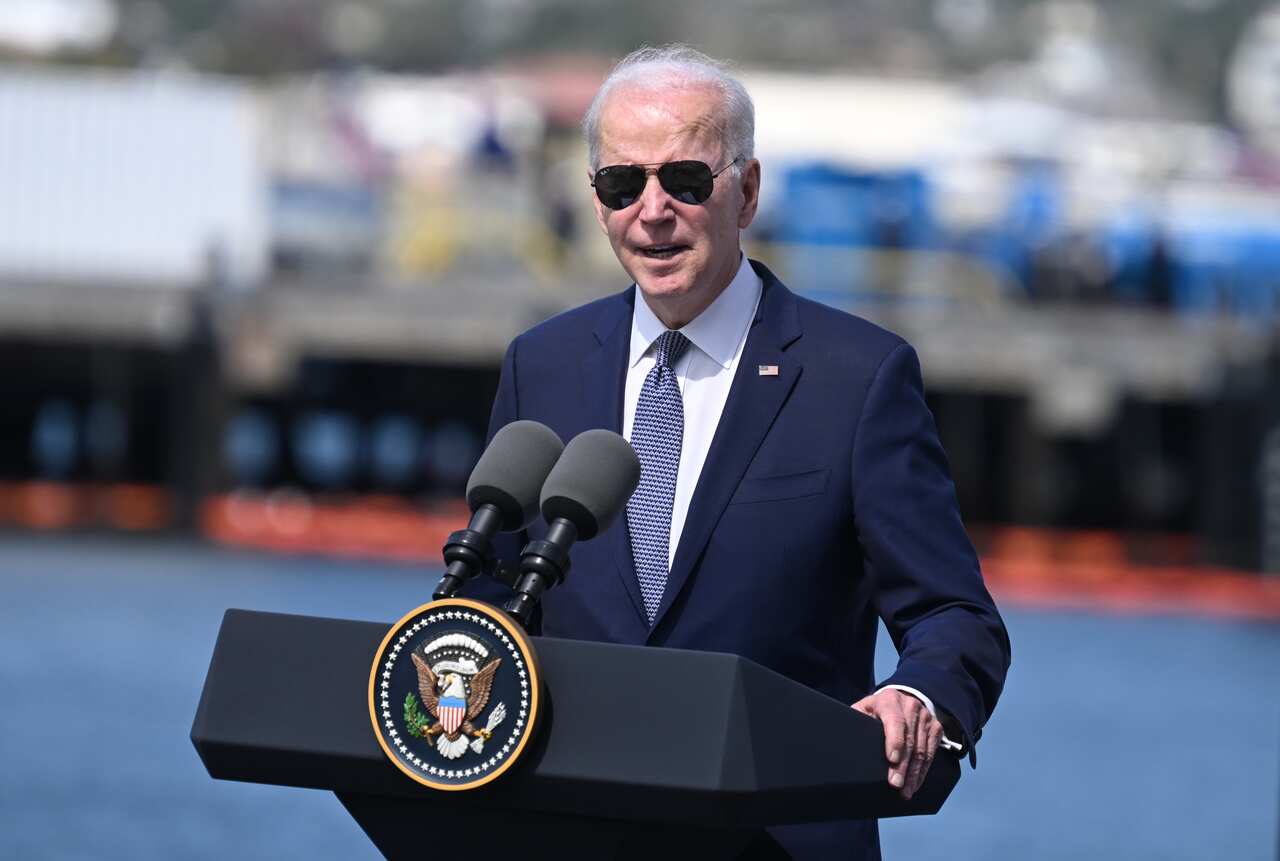 Man at a lecturn in sunglasses and suit. 
