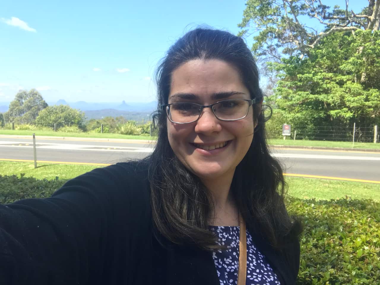 A woman with black hair and glasses smiles at the camera.