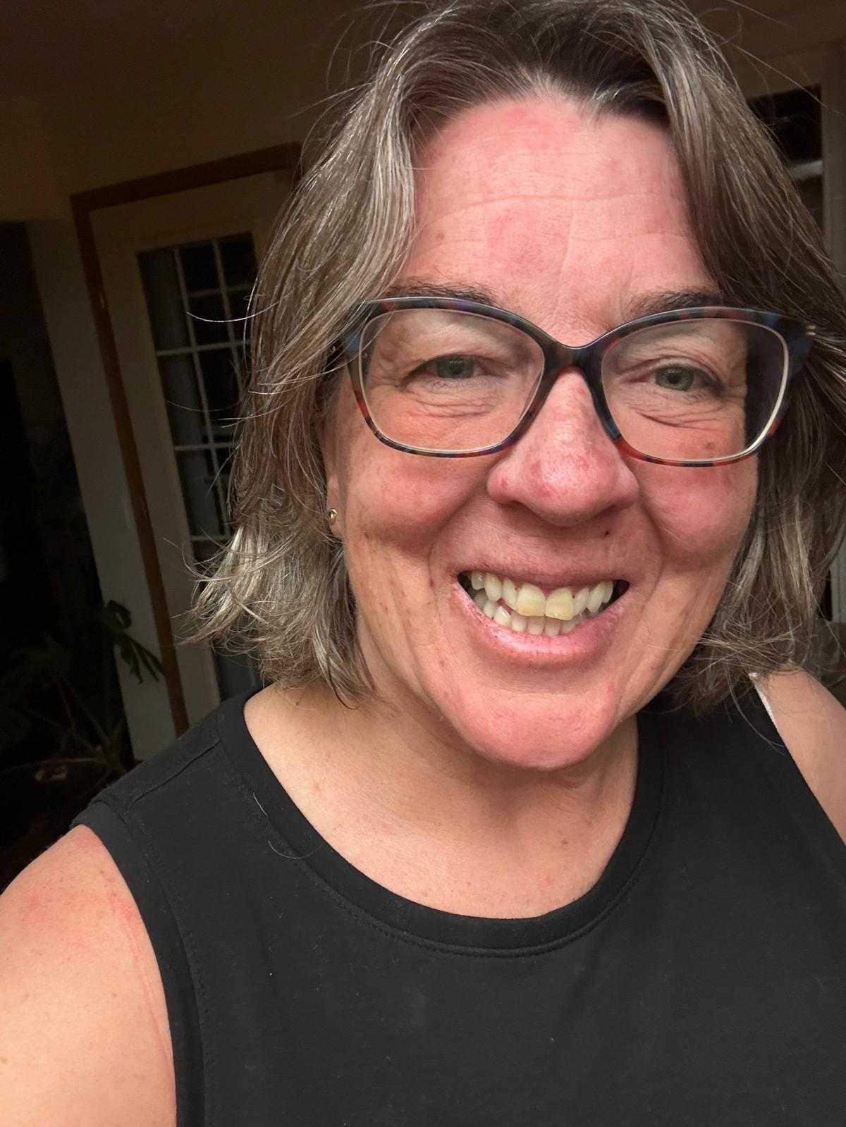 A middle aged white woman smiles at the camera.