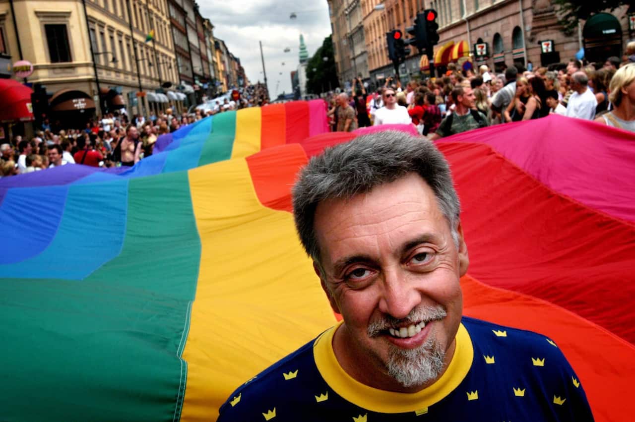 Man standing in front of rainbow flag in Stockholm