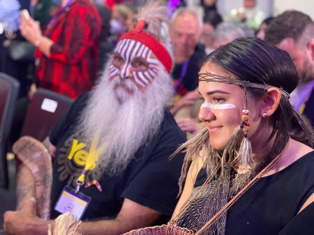 A girl and a man wearing Indigenous face paint