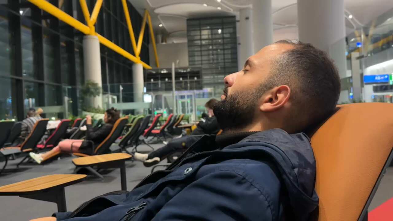 A man sitting in an airport with his eyes closed