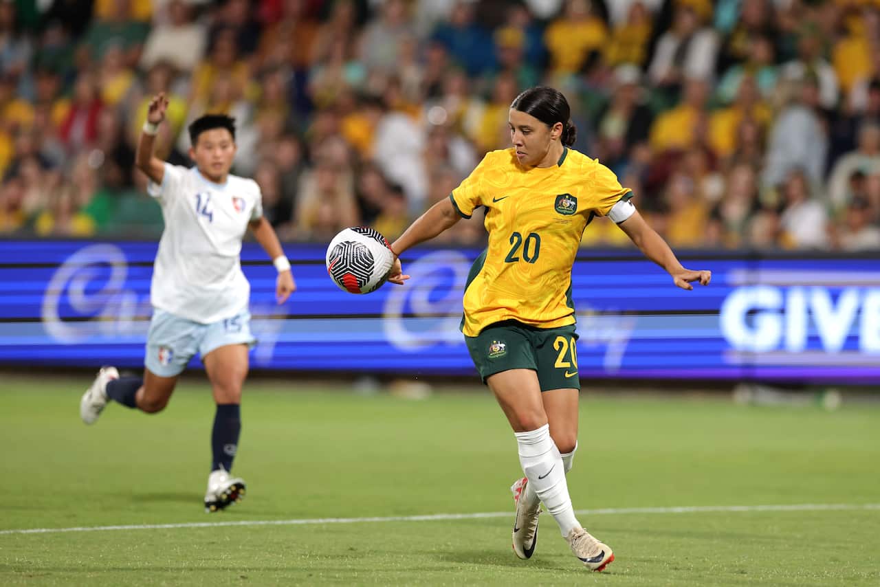 A woman approaches a ball while another player runs behind her
