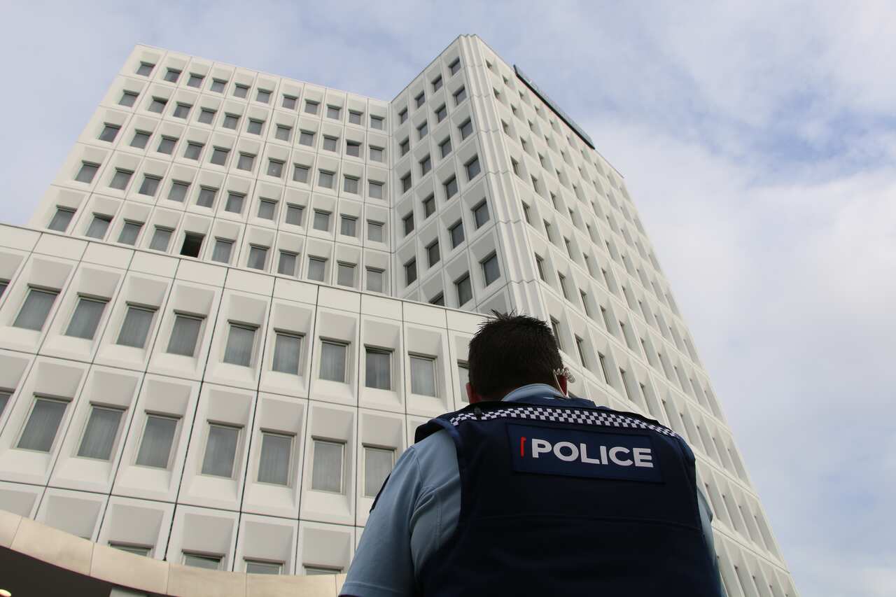 A New Zealand police officer standing outside a building.