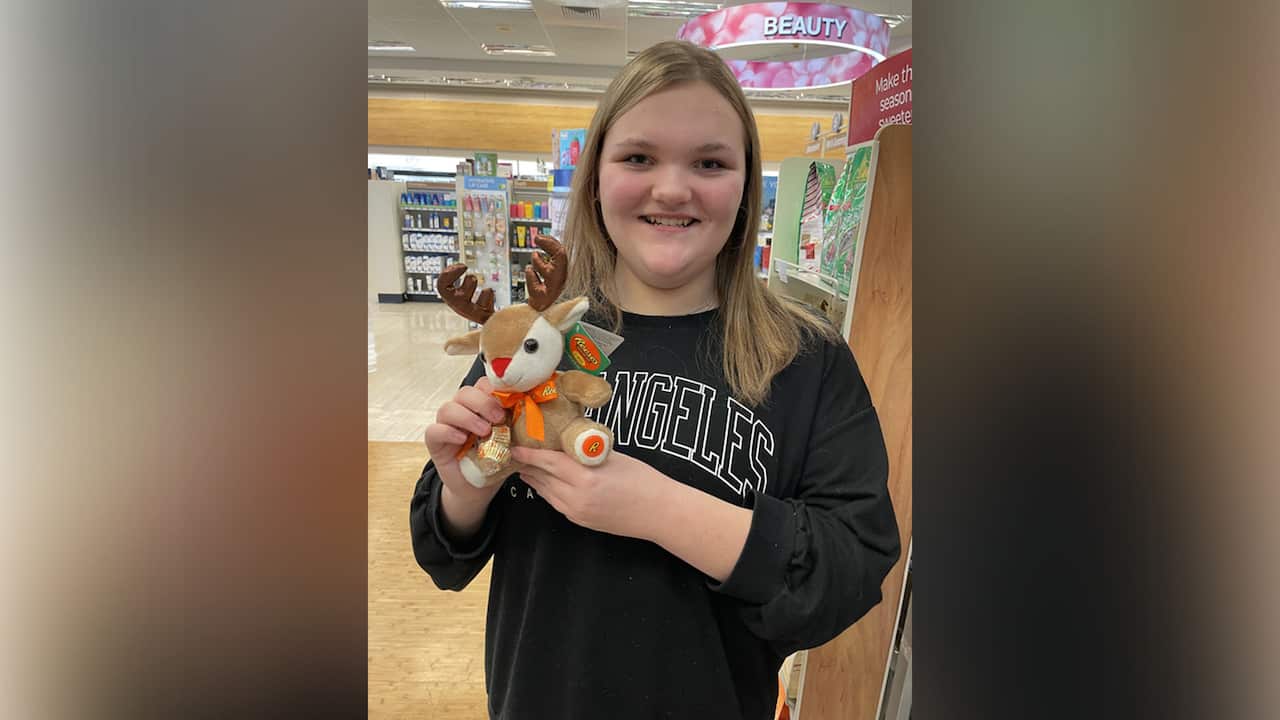A teenage girl in a black sweater holding a toy reindeer 
