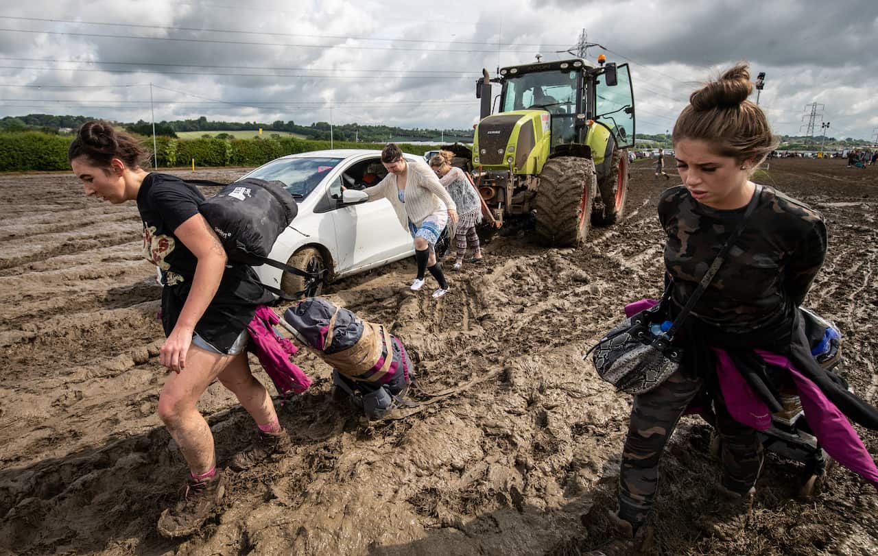 People drag luggage through the mud.