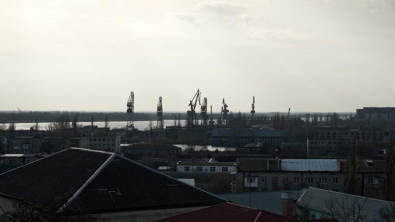 A grey-looking river snakes through an industrial-looking town, with grey skies overhead.