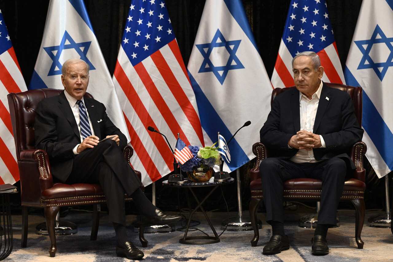 Joe Biden sits with Benjamin Netanyahu. American and Israeli flags are behind them.