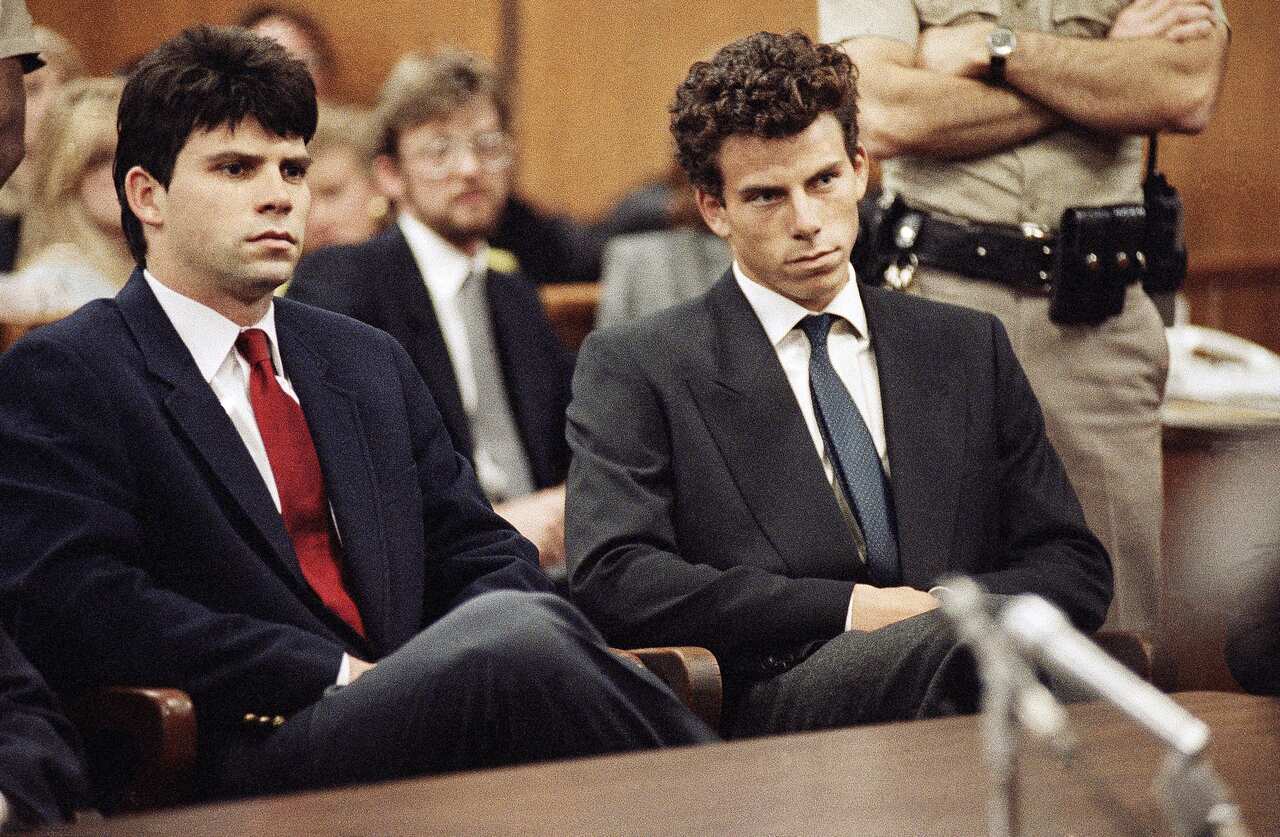 Two men wearing suits and ties sitting in a courtroom.