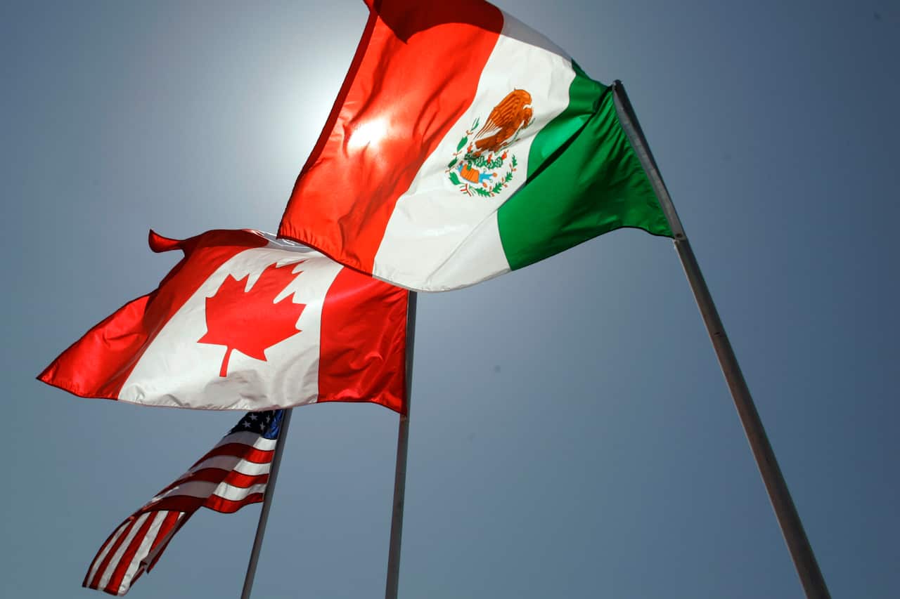 American, Canadian and Mexican flags fly in the air on poles.
