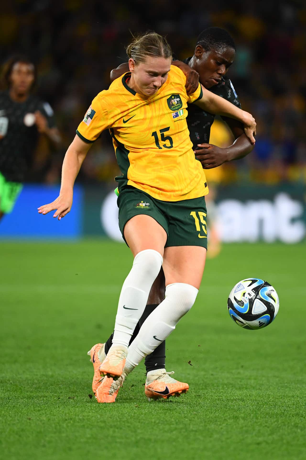 A woman in a yellow football shirt in front of a woman in a black football shirt