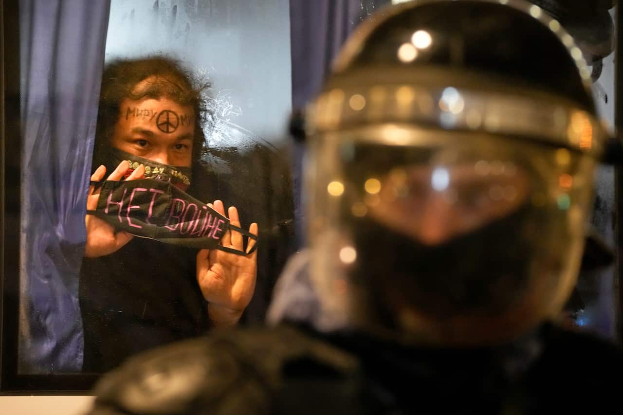 A detained demonstrator shows a sign 'No War!' from a police bus in St Petersburg