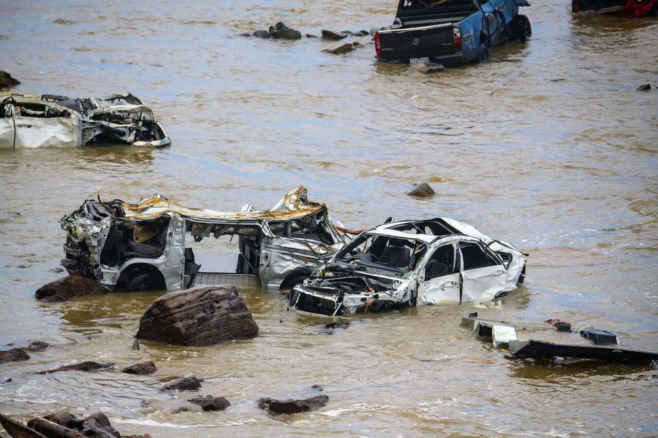 Heavily damaged vehicles in floodwaters.