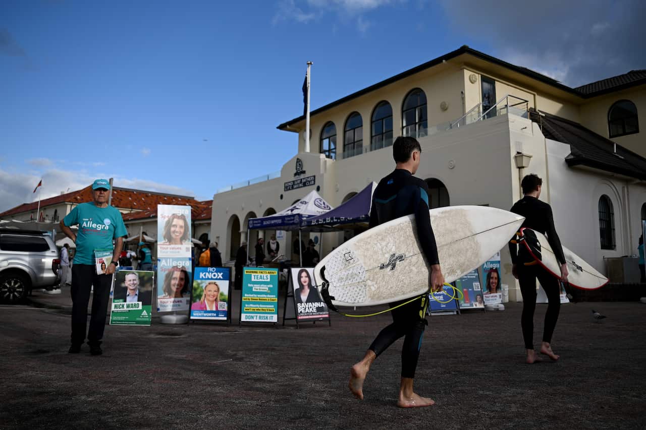 People with surfboards walking into a voting centre.