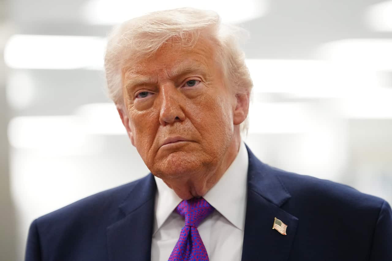 Donald Trump, wearing a blue blazer and American flag pin.
