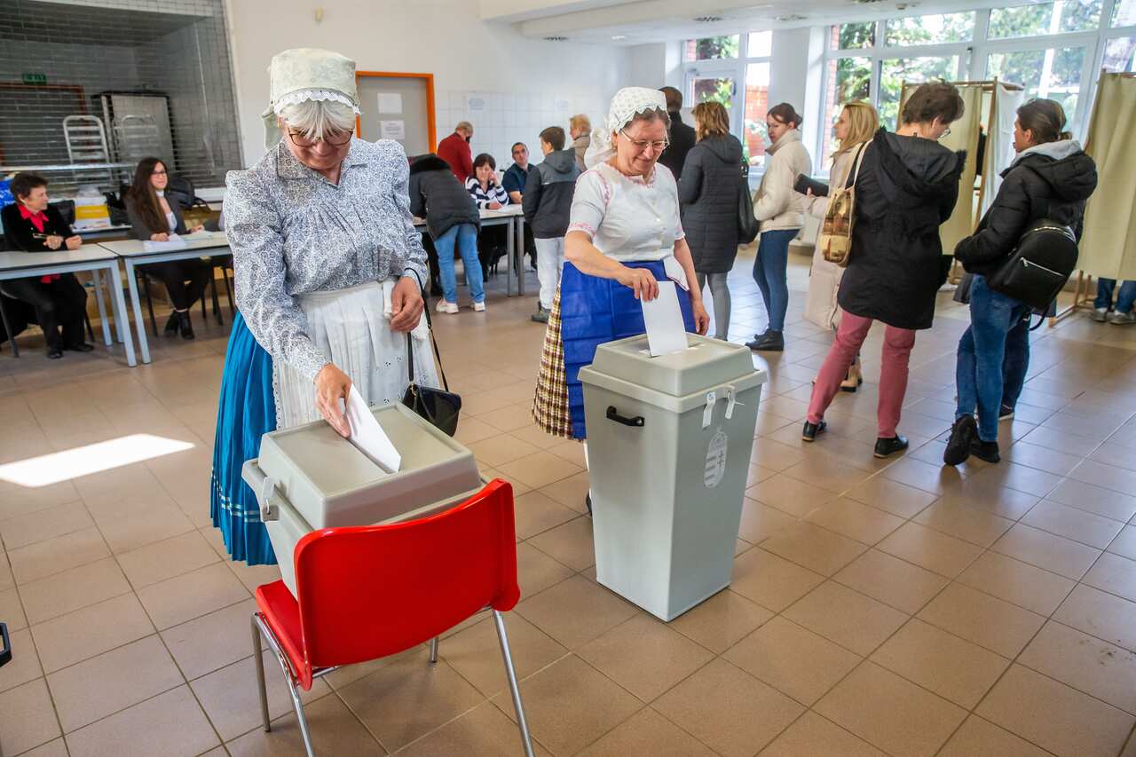 Women in traditional Hungarian dresses are seen casting their ballots at a polling station.