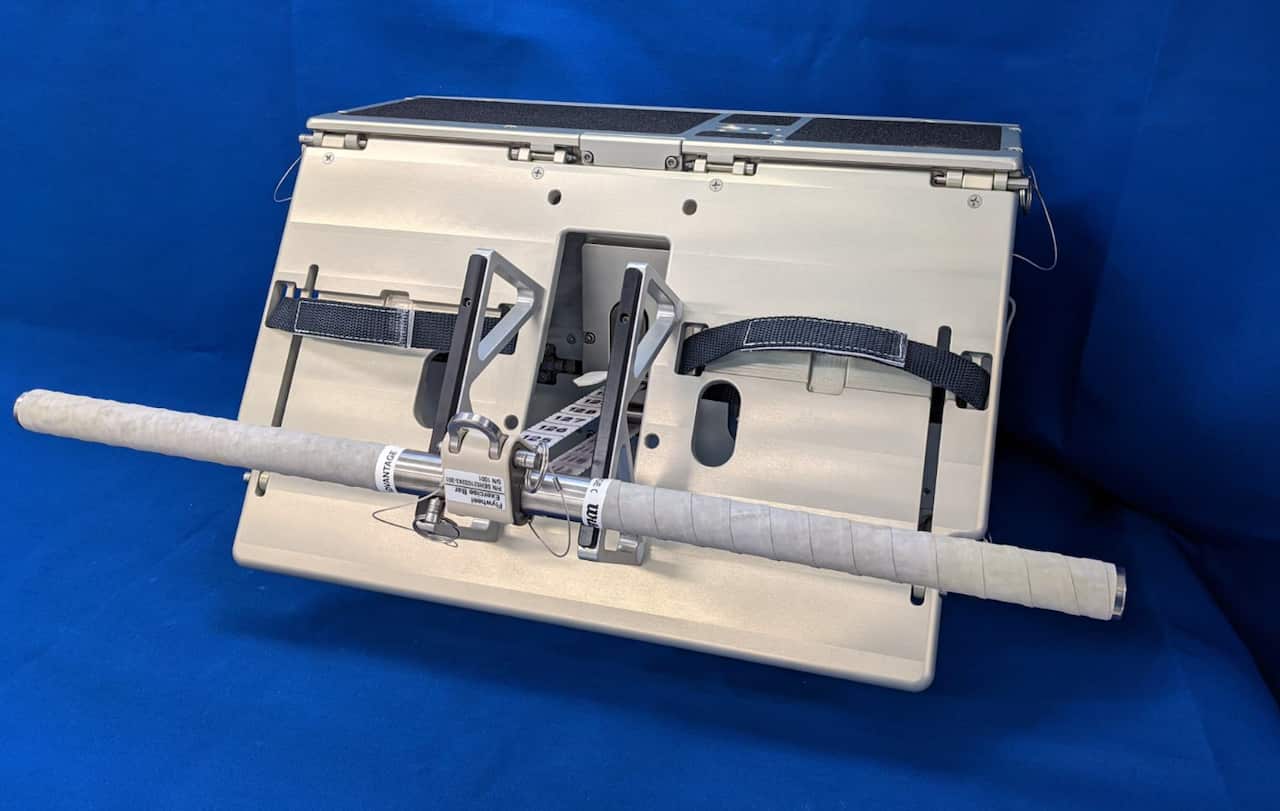 A high-tech, metallic NASA flywheel exercise device features a textured grip bar connected to a compact, angled base with straps for use in microgravity environments.