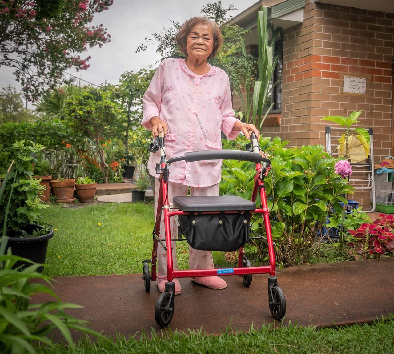 Catalina Macahron with her wheely walker in a garden.
