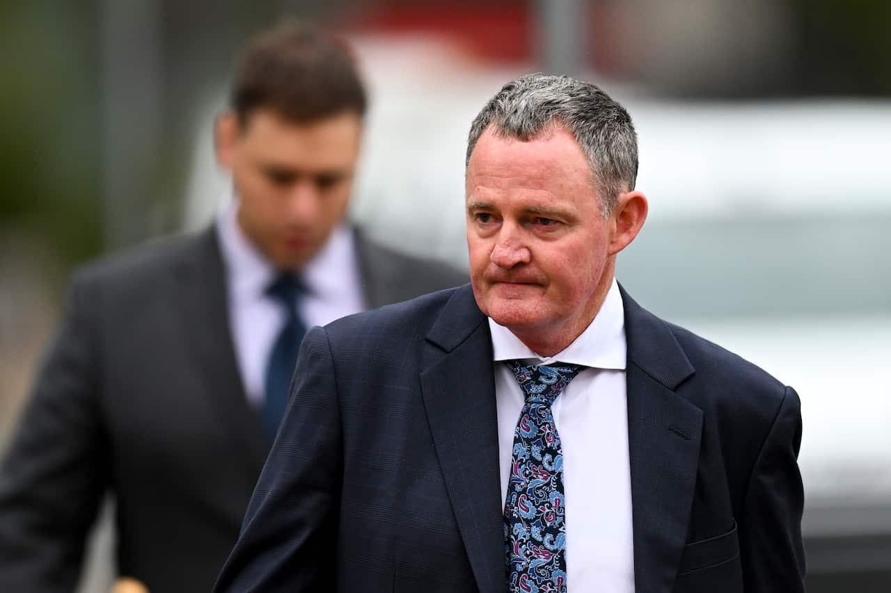 A man wearing a suit and tie walking outside.