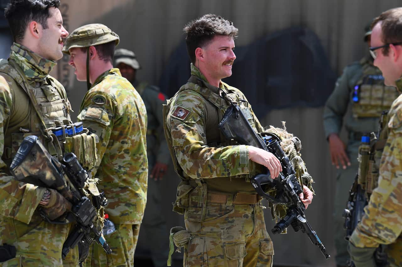 A group of troops wearing Australian Army uniforms and holding weapons.