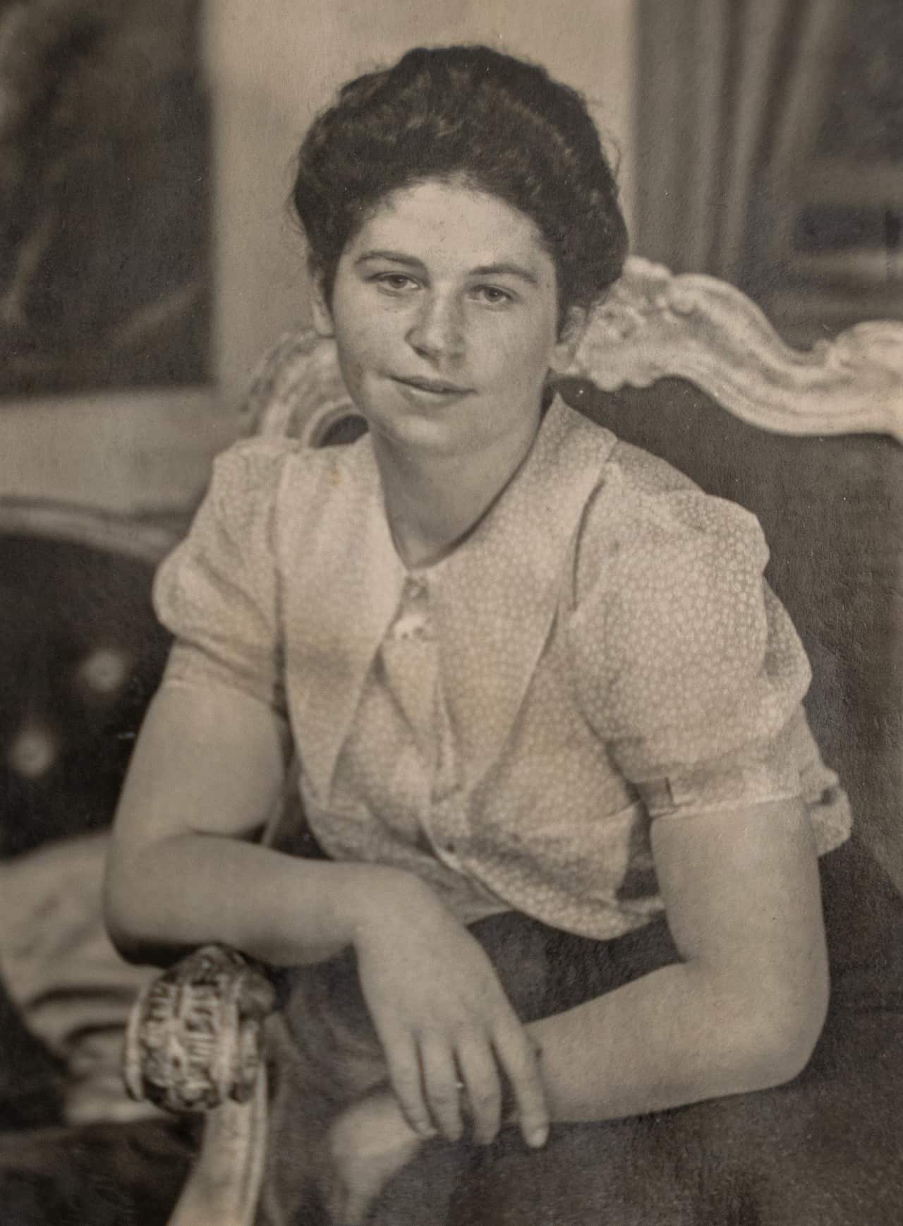 A sepia photo of a woman with folded arms smiling at camera.