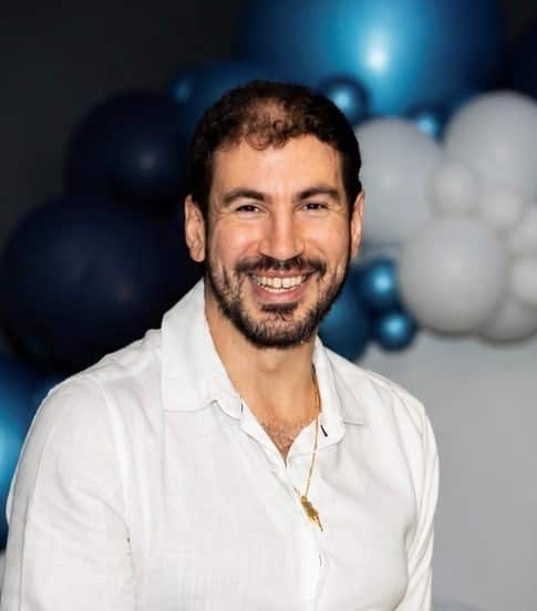 A photo of a man in a white shirt, smiling.