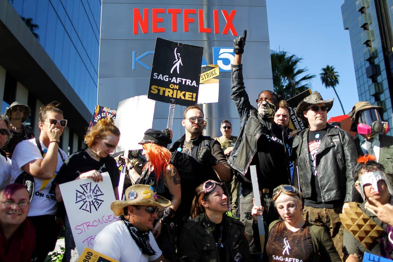 A group of protesters standing and sitting together, some with signs