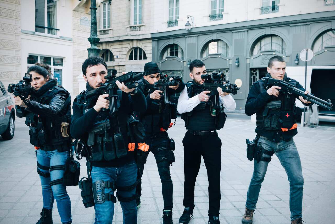 A group of police officers have their high tech guns up in the street
