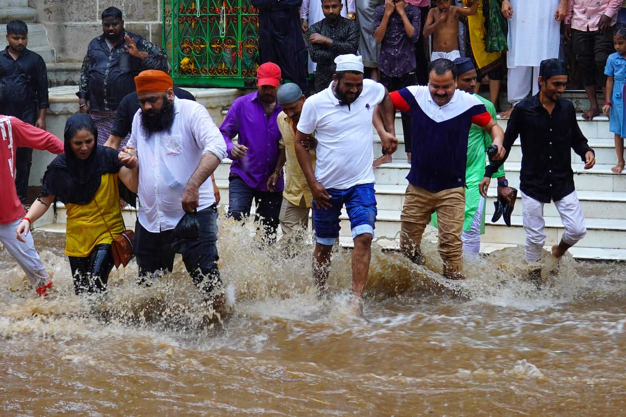 People walking through heavy monsoon rainfall in Rajasthan