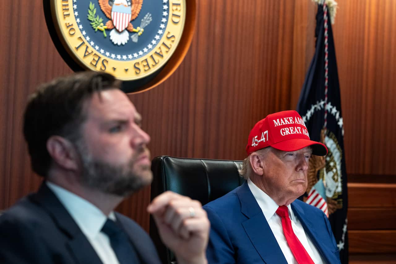 JD Vance and Donald Trump sitting on chairs next to each other.