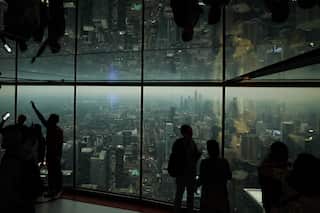 People look out from glass windows as smoke from wildfires blankets the city.