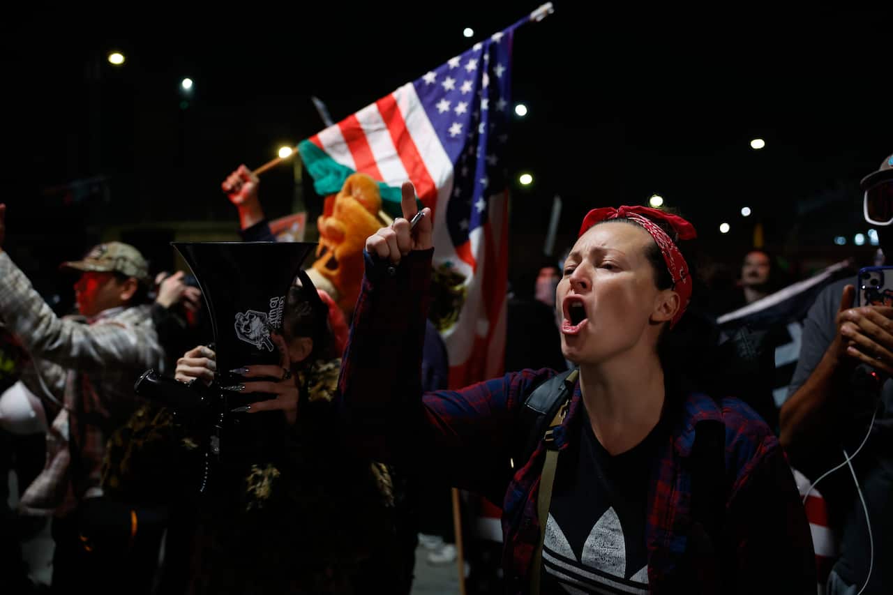 A group of angry protesters, one holding an American flag.