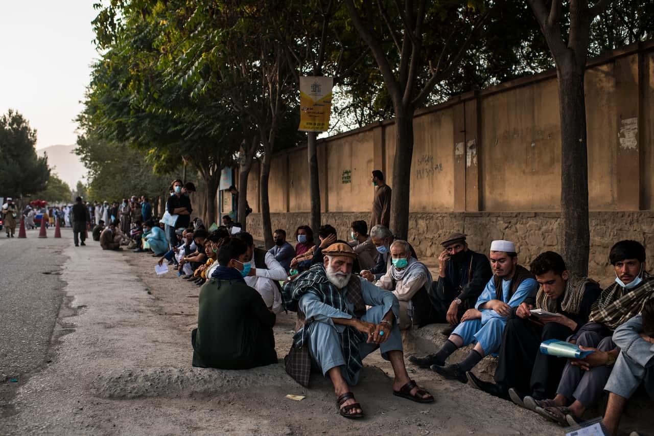 A queue of people sitting on the ground.