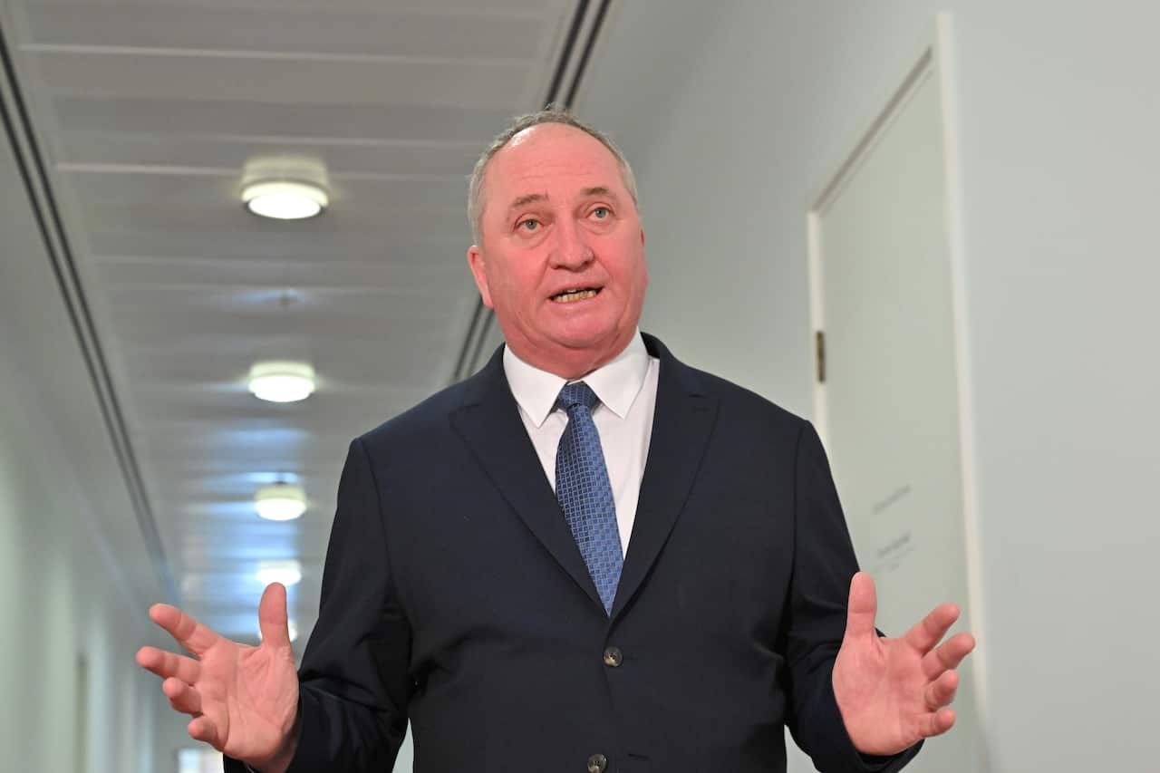 Barnaby Joyce, standing in a white hallway, with his hands out.
