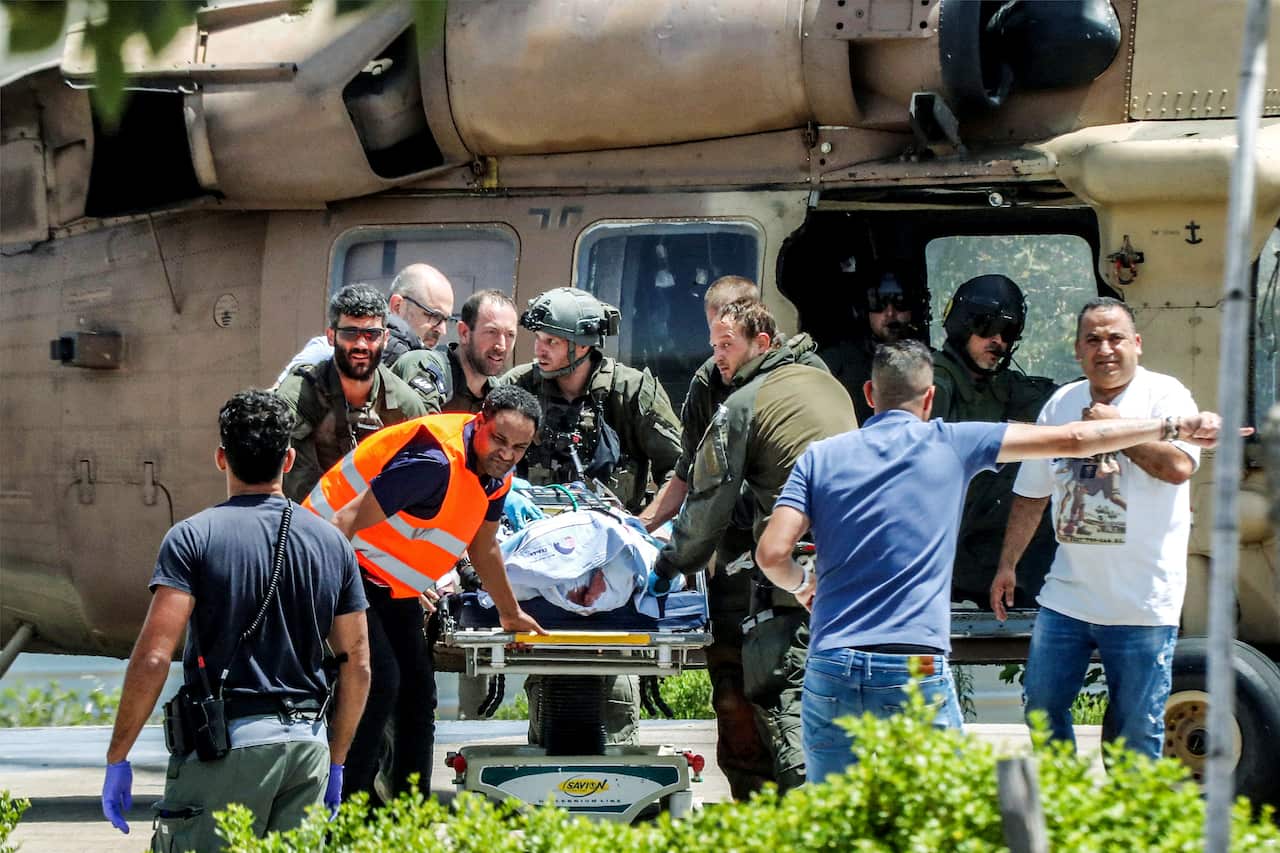 An injured person on a stretcher getting transported from a helicopter by people.