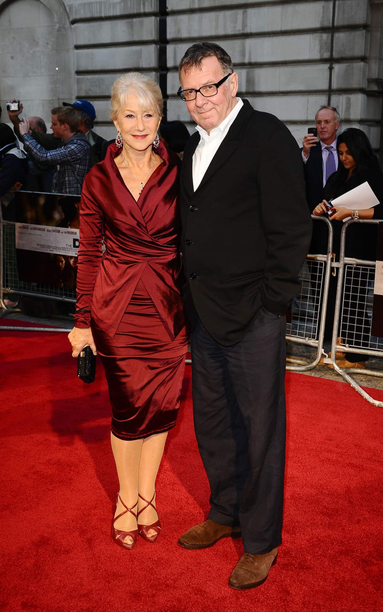 A man in black suit poses for a photo with a woman in a red dress.