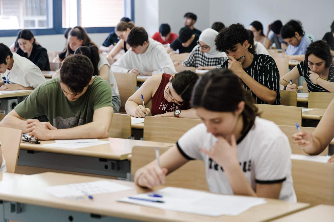 Several students are taking an exam inside a hall.