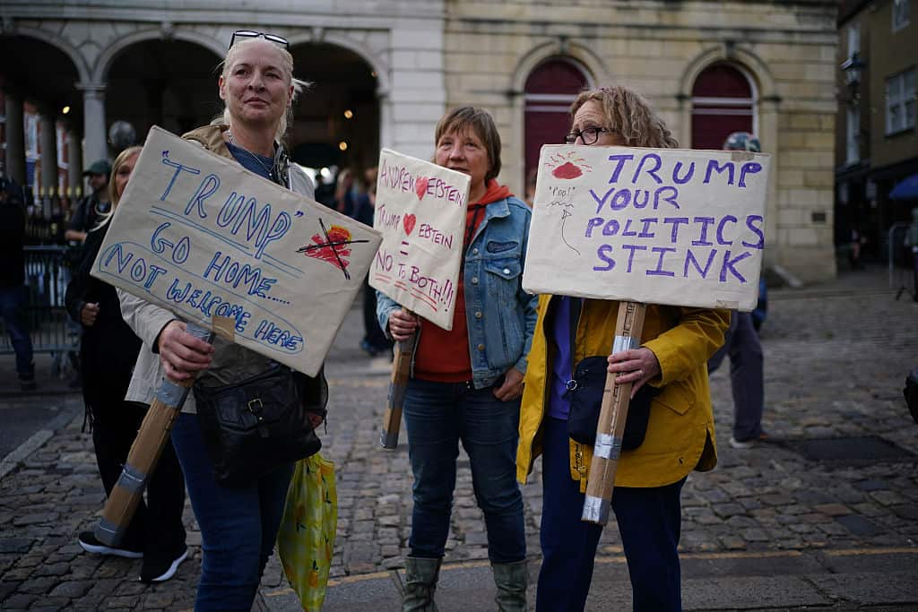 Three women hold placards protesting Donald Trump's visit to the UK