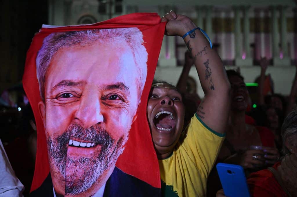A supporter of Mr Lula celebrates while holding a flag with his image printed on it