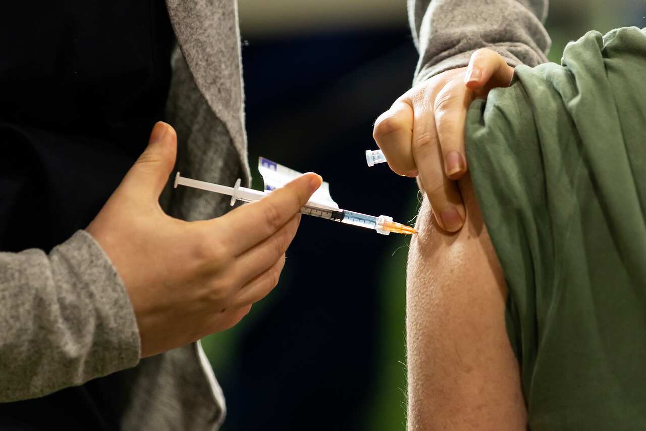 Close up of a needle being injected into someone's left shoulder